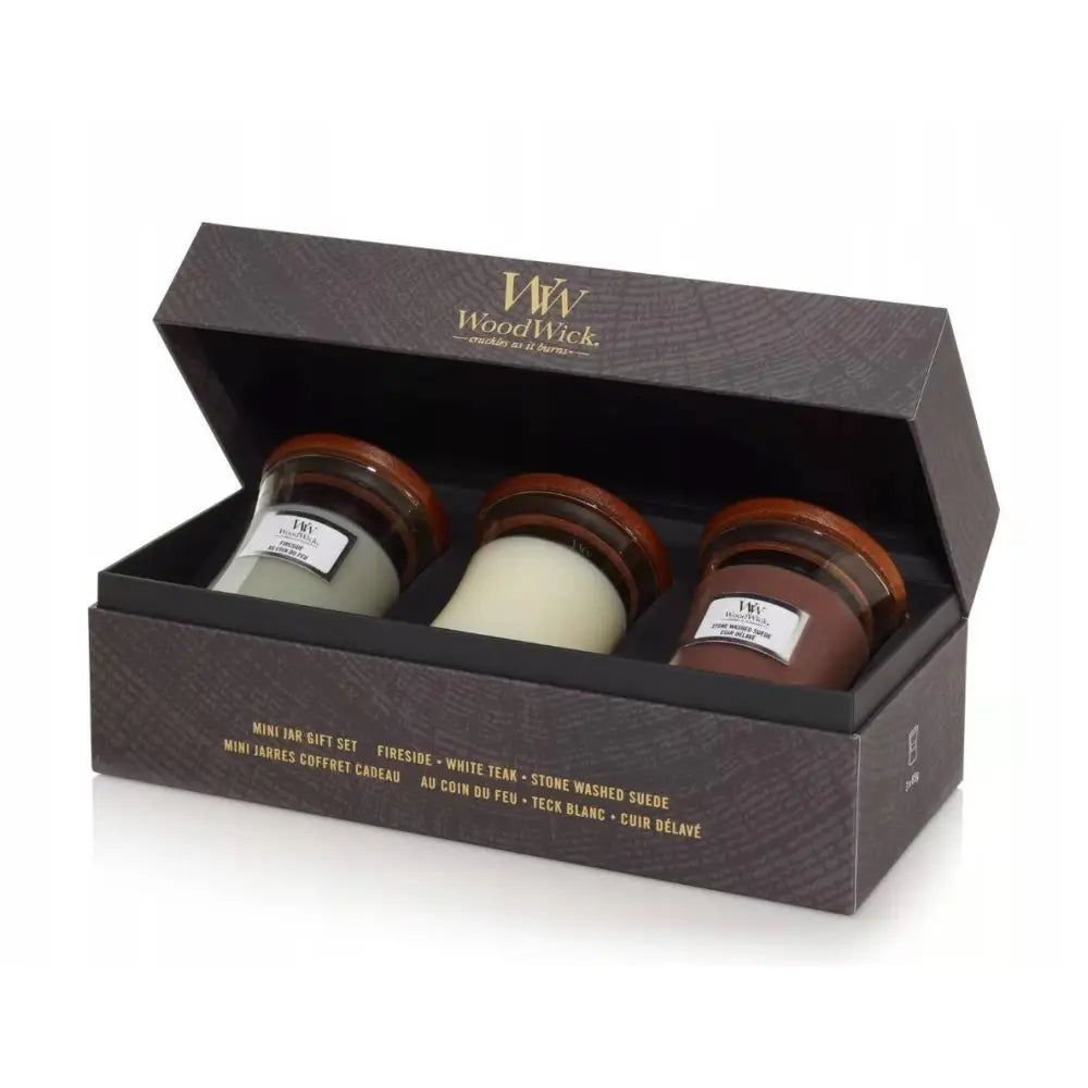 Woodwick gavesett med tre små duftlys i glass og trefargede lokk, pakket i mørk gaveeske med gulltekst.
