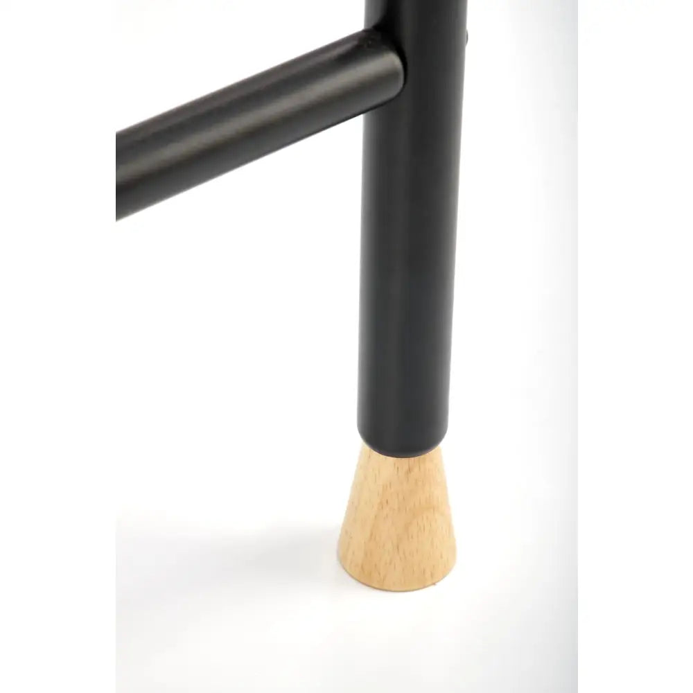 Naturlig kleshenger med sort metallben og lyst tre, nærbilde av markert overgang mellom materialene.