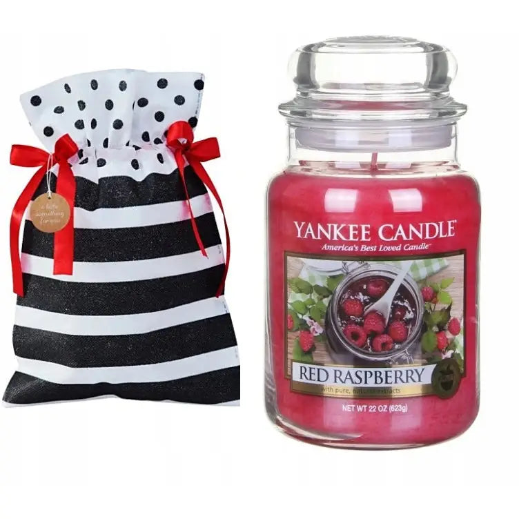 Yankee Candle Rød Bringebær duftlys i rosa glass med lokk, gavepose med røde silkebånd ved siden av.