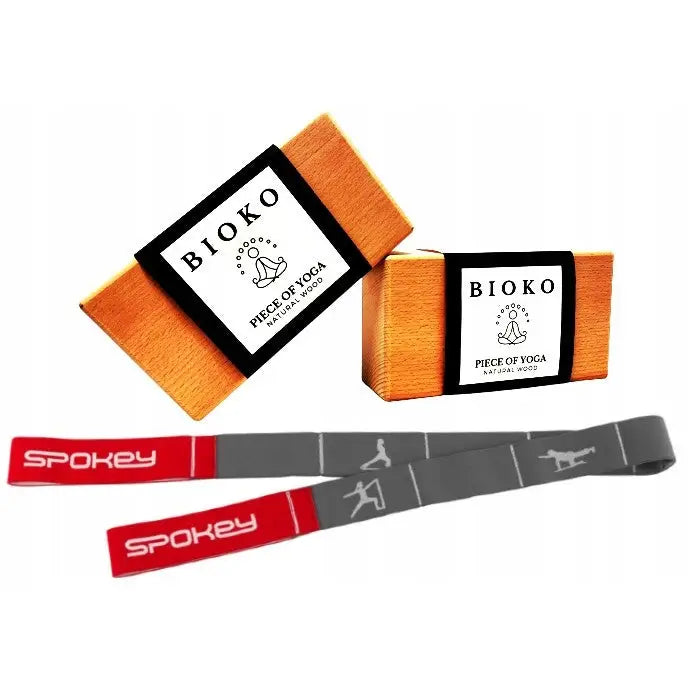 Yogaklosser i lyst tre med hvite etiketter og grå treningsstropp med røde ender og yogaposisjoner.