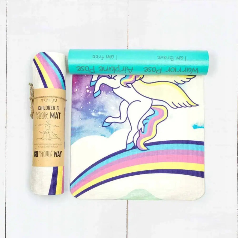 Yogamatte for barn Myga, rullet og delvis utrullet med regnbuedetaljer og pastellfarget enhjørning på hvit bakgrunn.