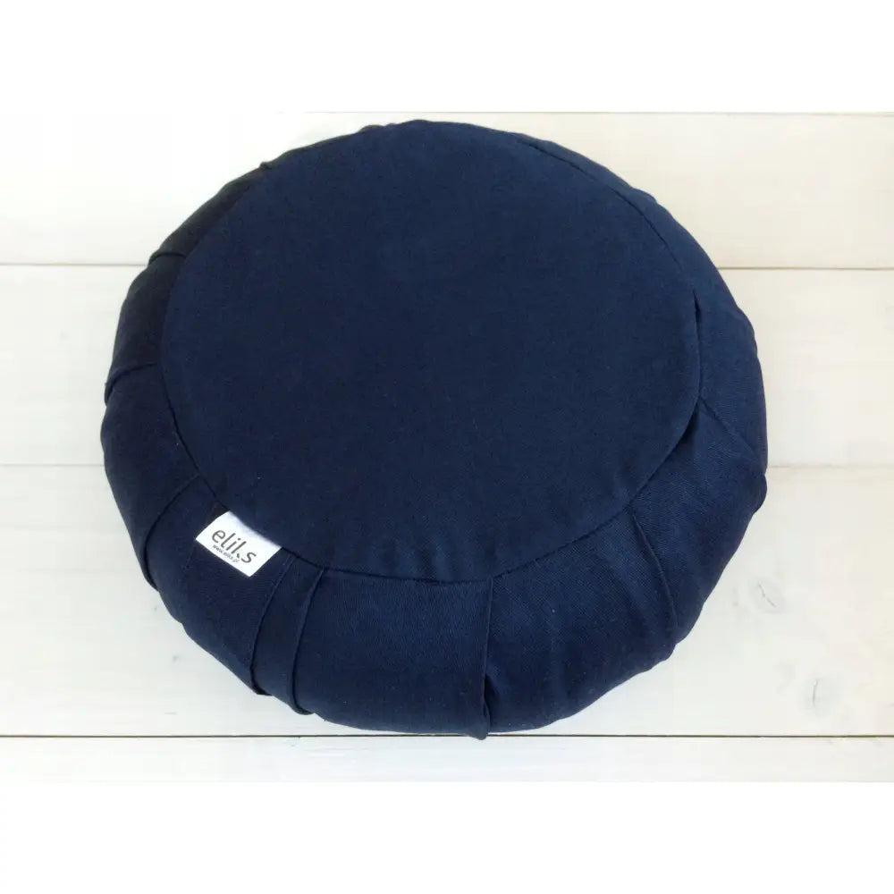 Zafu meditasjonspute med marineblått trekk, rund form sett ovenfra, hvit etikett synlig på siden.