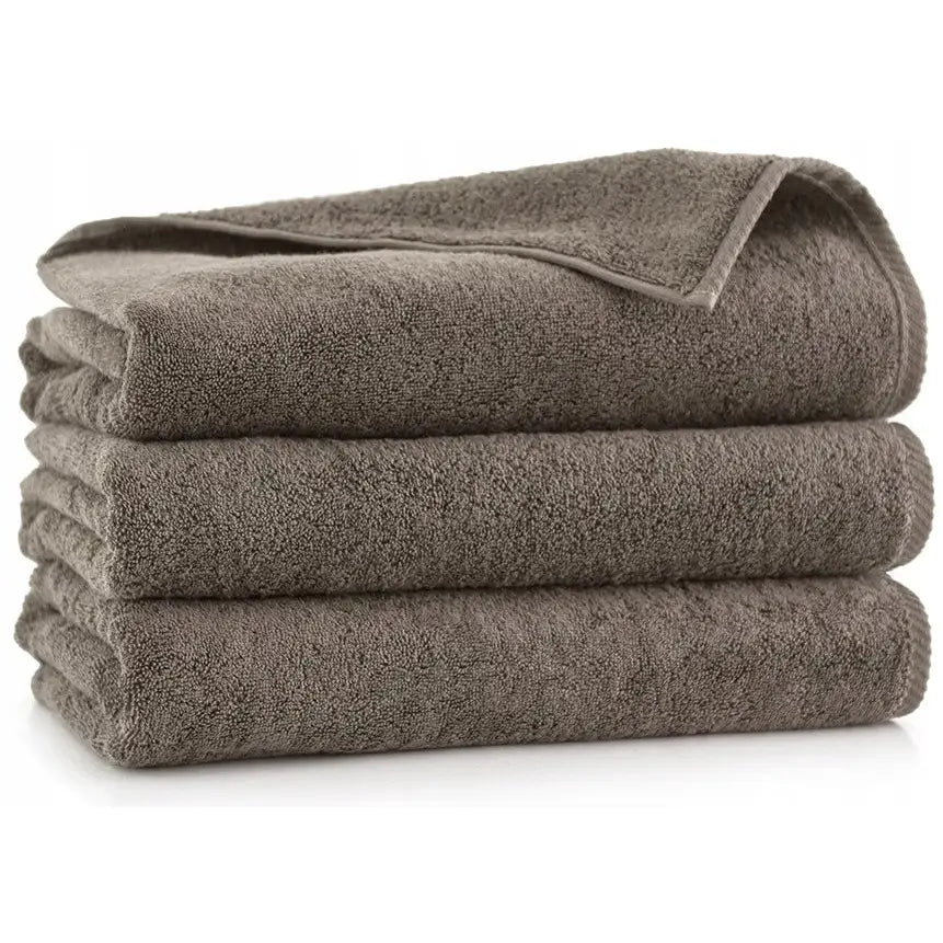 Zwoltex tykke kiwi håndklær, tre brune frottéhåndklær pent stablet fra siden mot hvit bakgrunn.