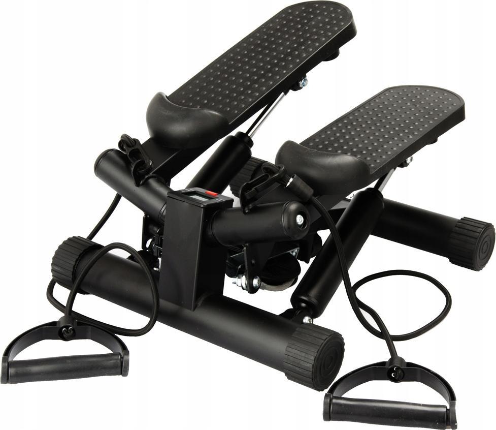 Stepmaskin med to sorte tråkkpedaler, håndtak, motstandsbånd og LCD-display mellom pedalene, sett skrått forfra.