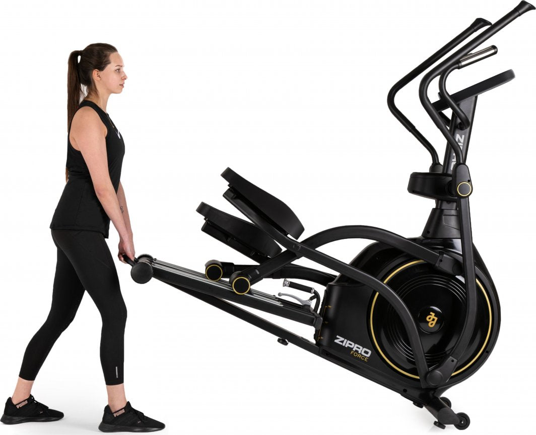 Ellipsemaskin Trening trilles av en kvinne, maskinen er sort med gule detaljer og står på hjul for enkel flytting.