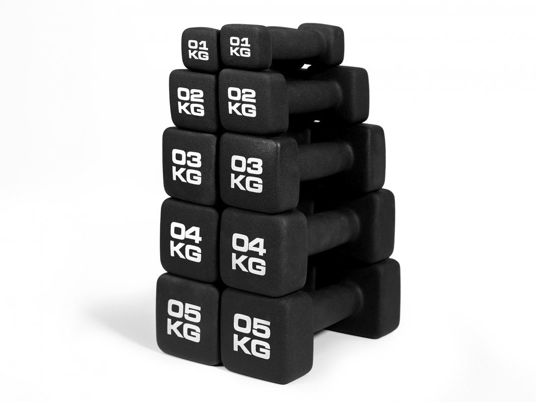 Manualer i sort neopren med hvit tekst, stablet i en søyle fra 1 til 5 kg, sett fra skrå vinkel.