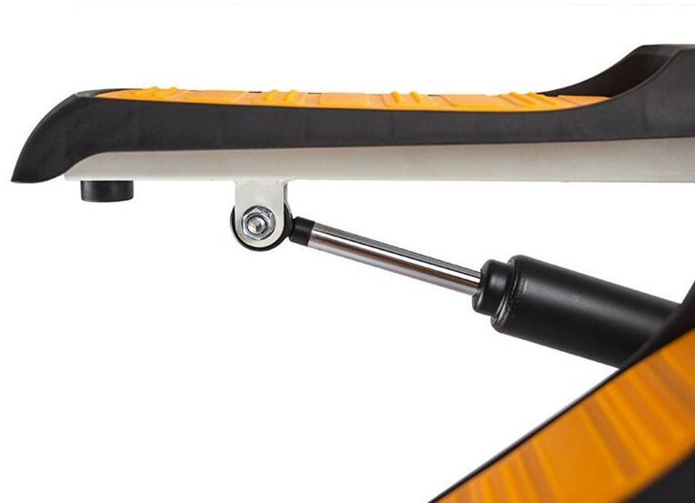 Stepper med oransje og sort fotpedal med antiskli-mønster, gassfjær og metallfeste synlig under pedalen.