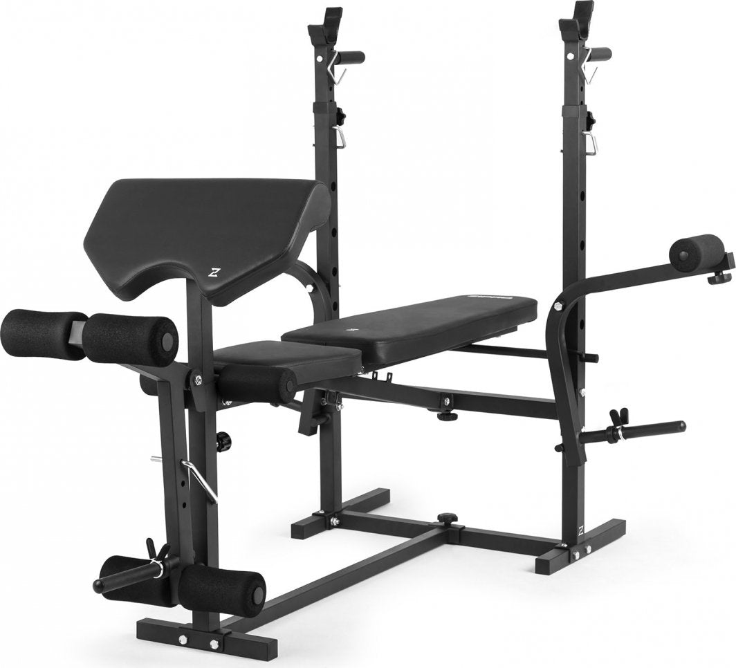 Multifunksjonell Treningsbenk i sort stål med vektstativ, biceps curl-pult og benstøtte, sett fra skrå vinkel.