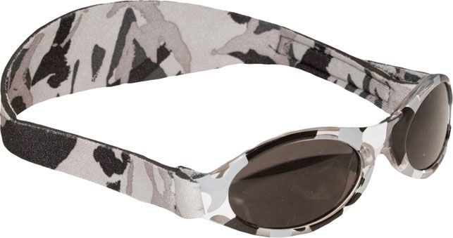 Solbriller Barn med mørke glass og elastisk stropp i grå, hvit og svart kamuflasjemønster, sett fra skrå vinkel.