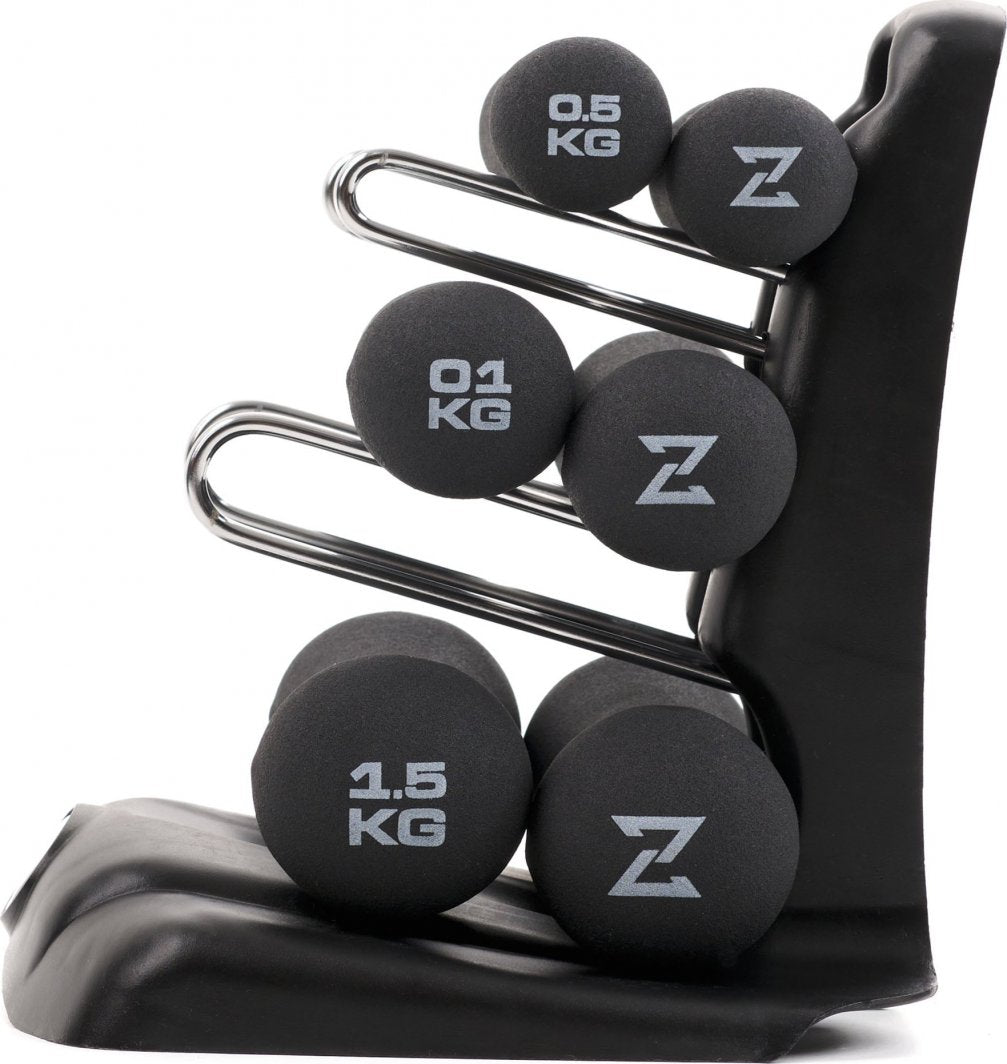 Hantler i sort neopren, seks stykker med hvit vektmerking, plassert i stativ med tre metallholdere, sett fra siden.