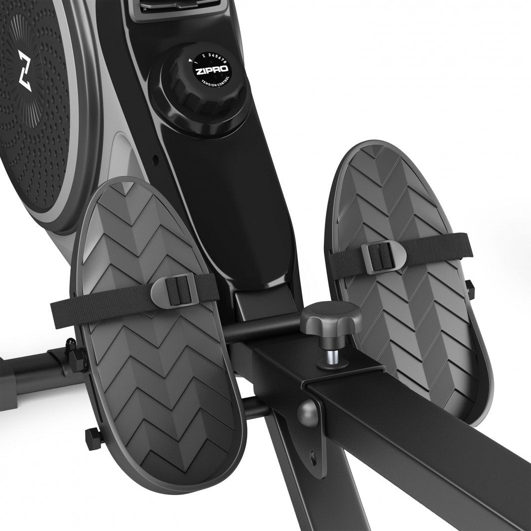 Romaskin med to svarte og grå fotplater med justerbare stropper, ramme og kontrollknapp synlig i nærbilde.