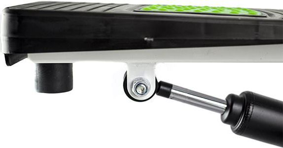 Mini Stepper med grønt sklisikkert pedalbelegg, synlig fjæringsmekanisme og hjul sett fra siden.