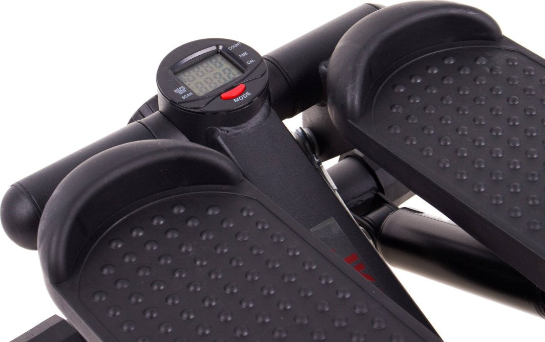 Stepmaskin i sort plast og metall, sett ovenfra med sklisikre fotplater og digital skjerm med rød knapp.