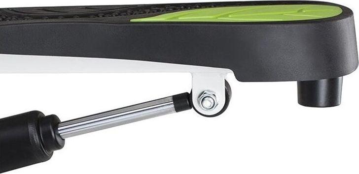 Mini Stepper med sort og grønn overflate, viser sidevisning av metallstang med demper og solide festekomponenter.
