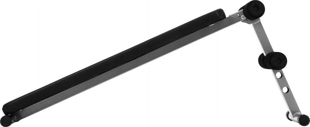 Treningsbenk med skrå rygg, svart polstring, justerbare ben og skumruller, sett fra siden.