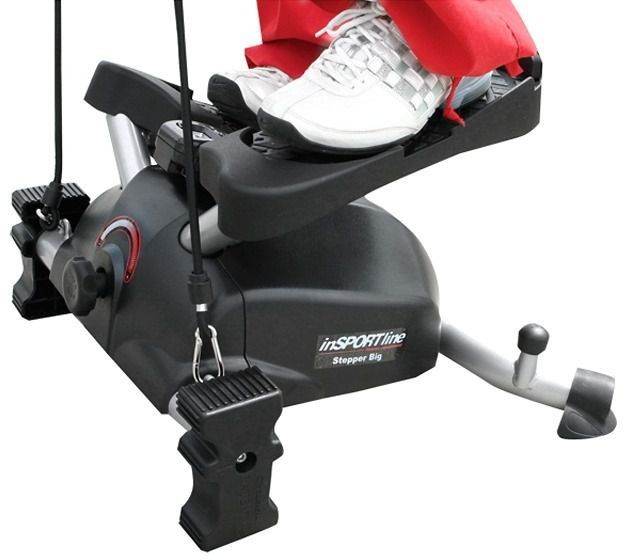 Mini Stepper i sort med LCD-display, brukt av person med hvite joggesko og røde bukser, sett fra siden.