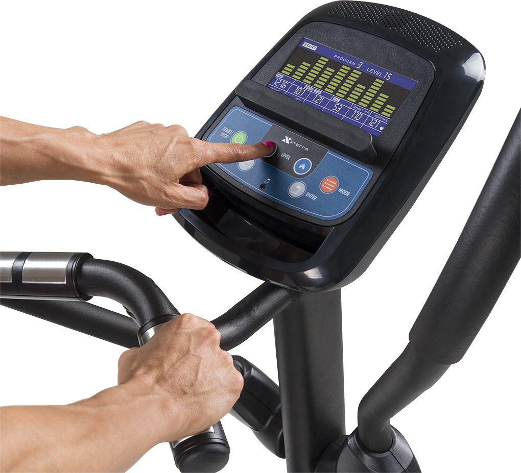 Ellipsemaskin Trening konsoll sett ovenfra med LCD-display, knapper og håndtak, en hånd trykker start/stopp.