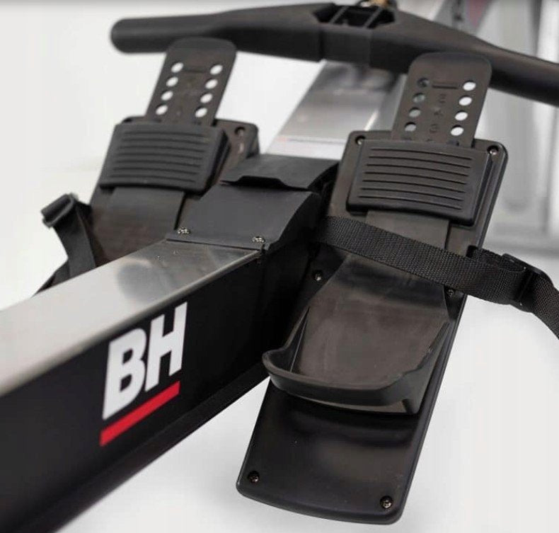 Romaskin med to justerbare sorte fotplater med remmer, montert på metallramme, sett fra skrå vinkel.