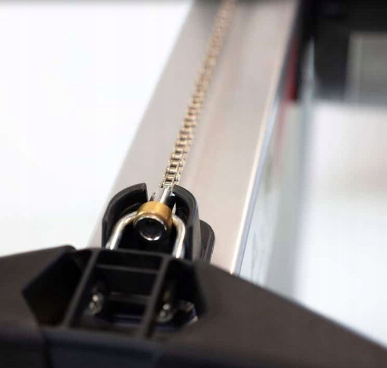 Romaskin Trening med nærbilde av metallkjede på aluminiumsskinne, sorte og messingfargede detaljer vises tydelig.