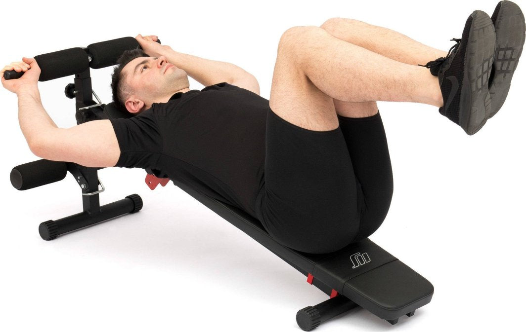 Sammenleggbar Treningsbenk med svart polstring, ståldetaljer og person som gjør mageøvelse liggende på benken.