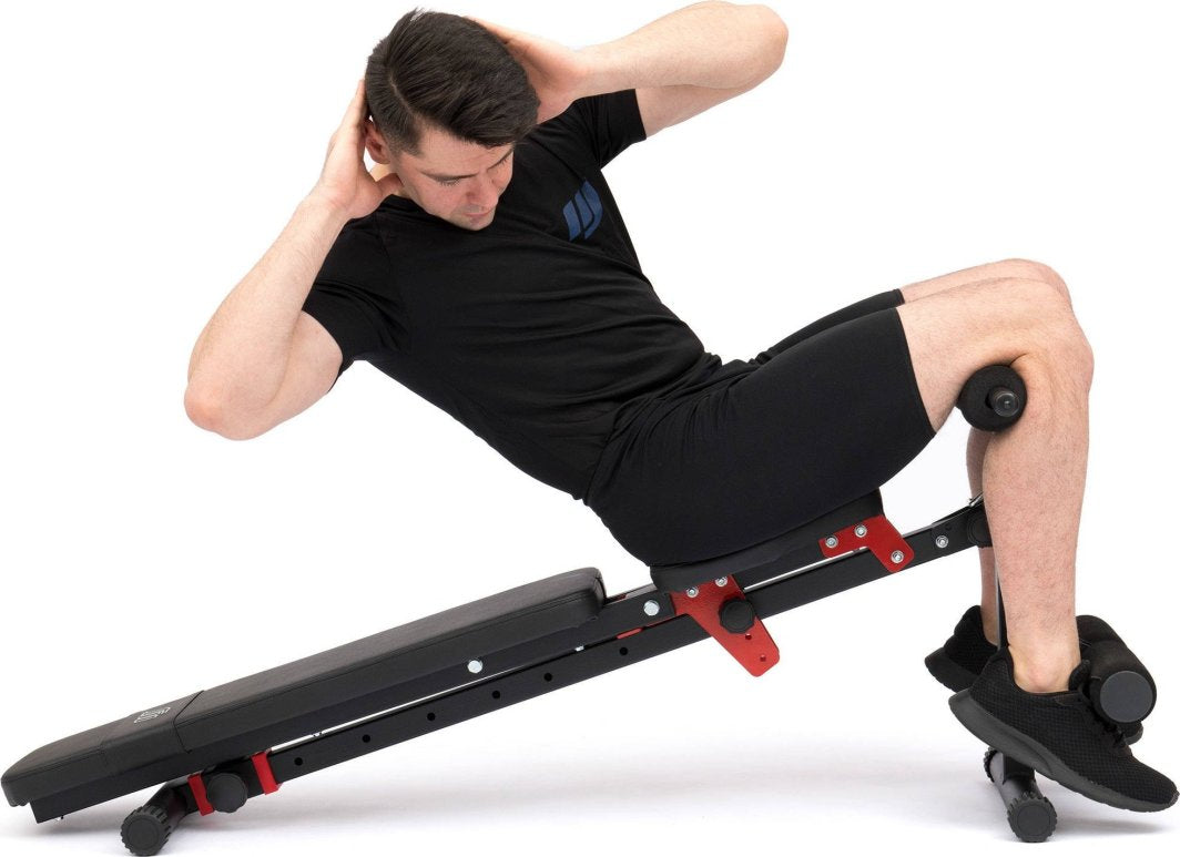 Sammenleggbar Treningsbenk i svart og rødt metall, sett fra siden med person som gjør sit-ups, justerbar vinkel.