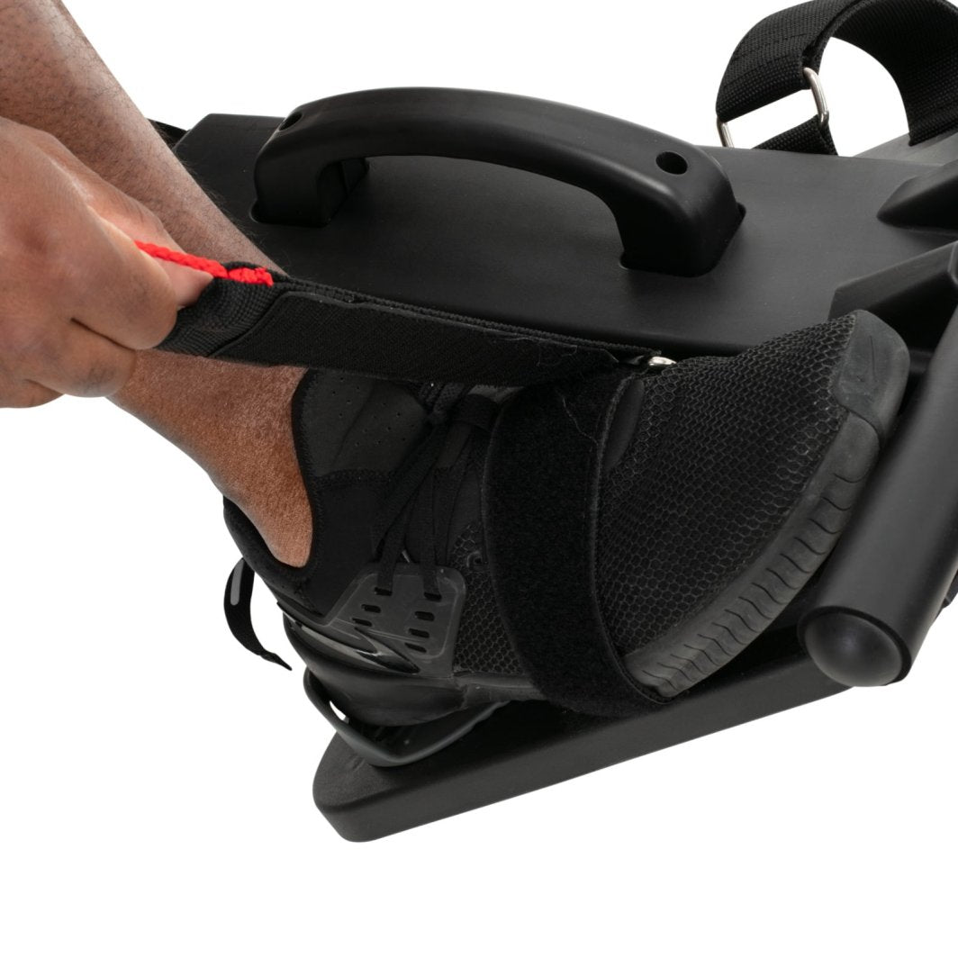 Romaskin Sammenleggbar sort treningssko festes med borrelåsrem, hånd strammer rød stropp rundt foten.