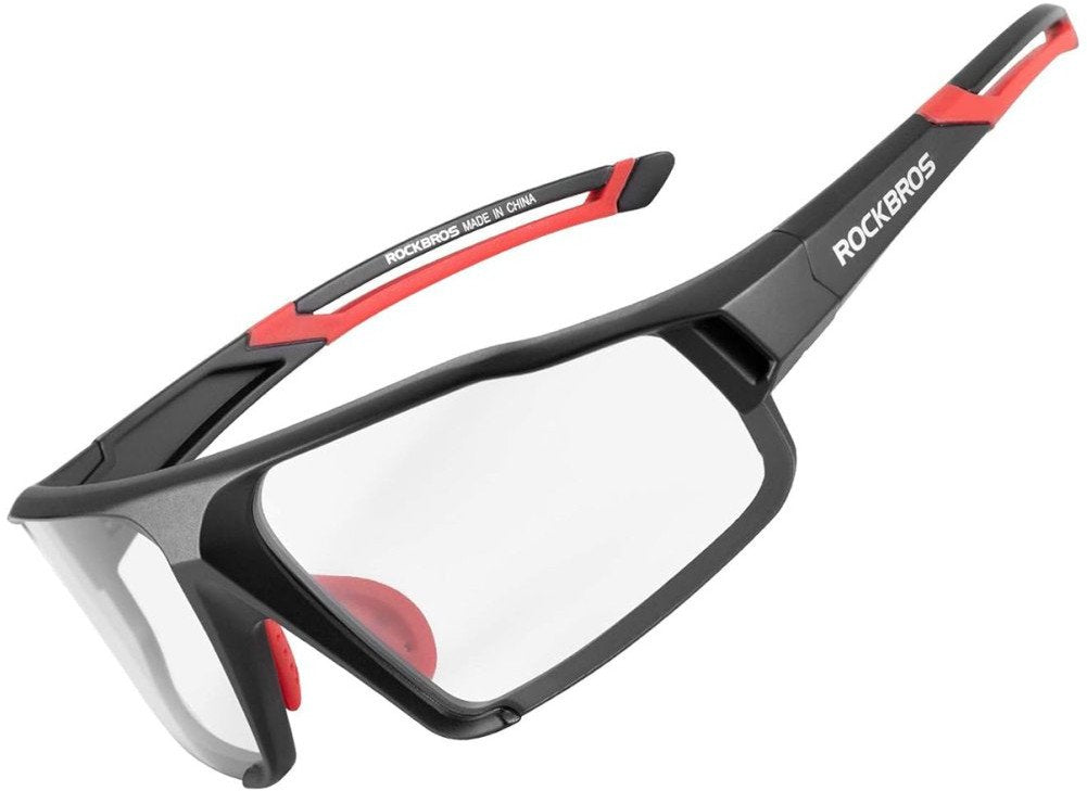 Sykkelbriller i sort plast med røde detaljer, gjennomsiktige glass og halvramme, Rockbros-logo synlig på siden.