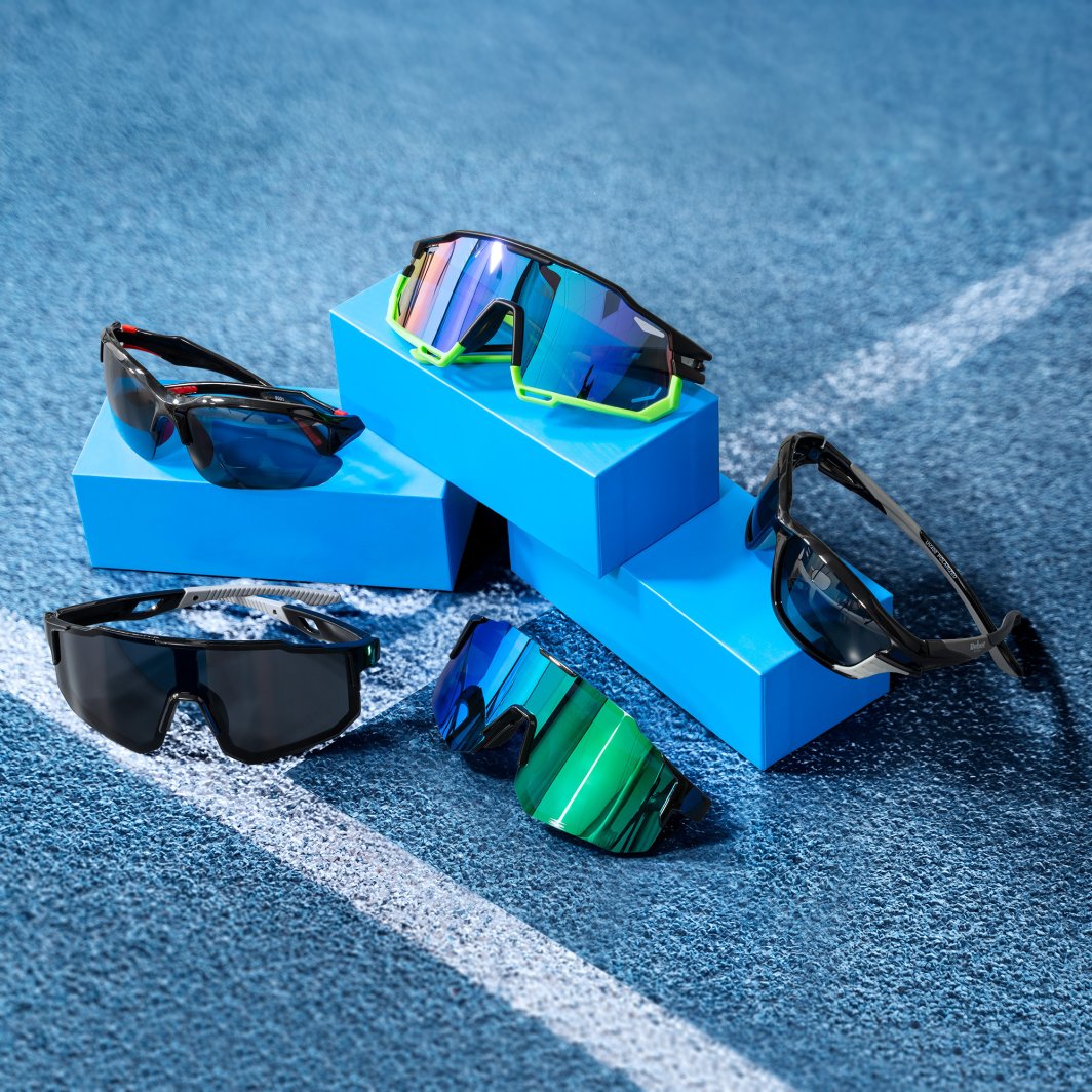 Solbriller med speilglass og sorte rammer, noen med fargedetaljer, ligger på blå esker mot blått underlag.