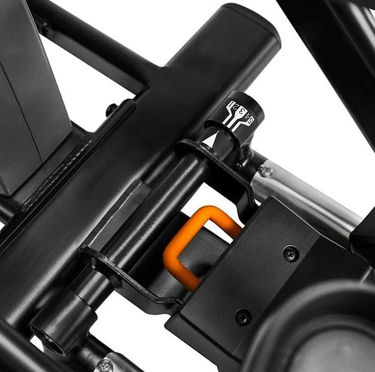 Cross Trainer detaljbilde av sort justeringsmekanisme med oransje håndtak og tall på dreieknapp, skrå vinkel.