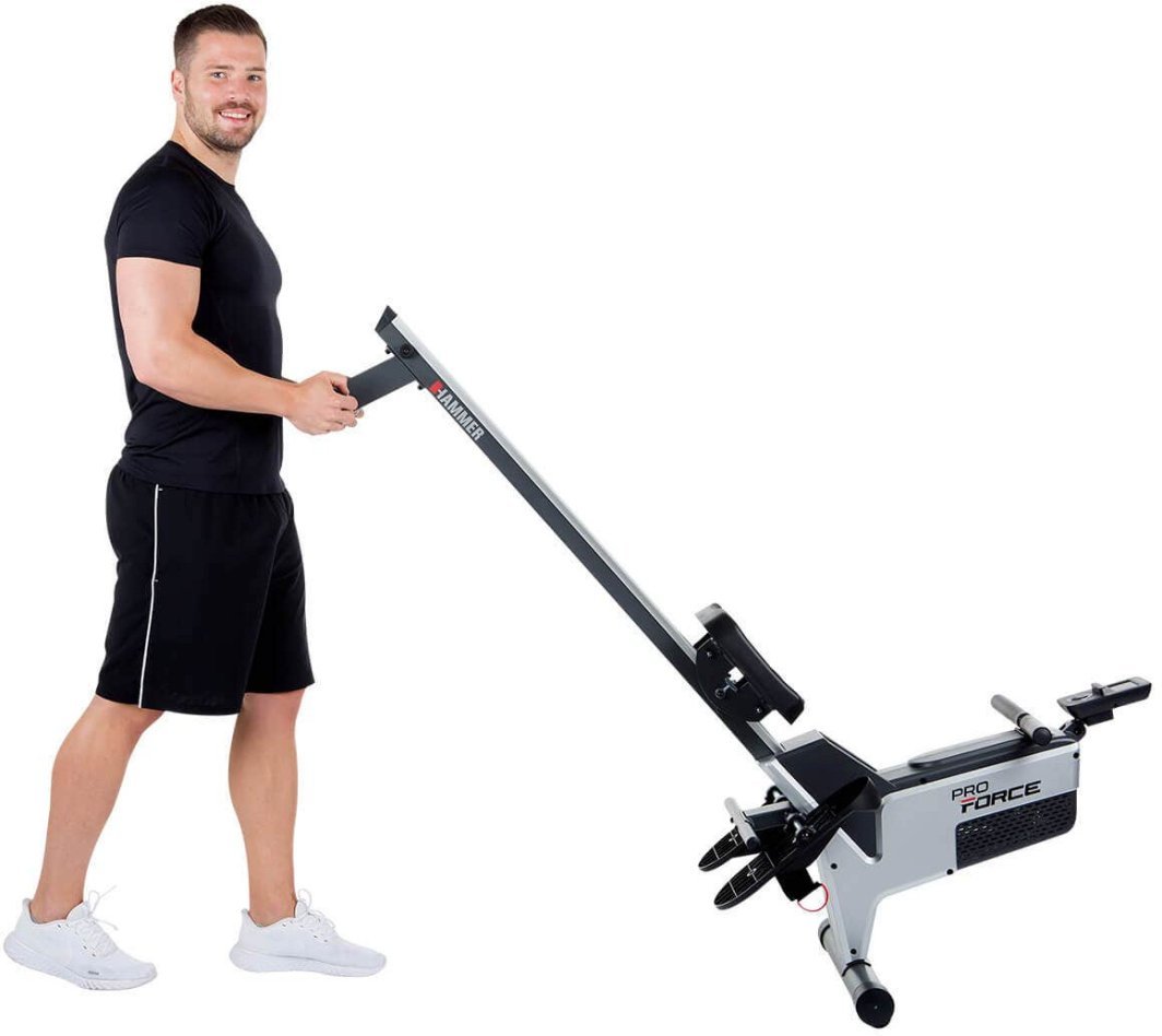 Romaskin Trening sammenfelt og trilles av en mann, sett fra siden, med hjul og tydelige pedaler.