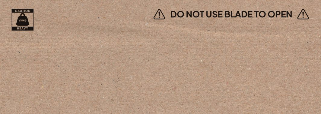 Sittesykkel brun pappeske med advarselstekst, tungt-løft symbol og beskjed om å ikke bruke kniv, sett ovenfra.