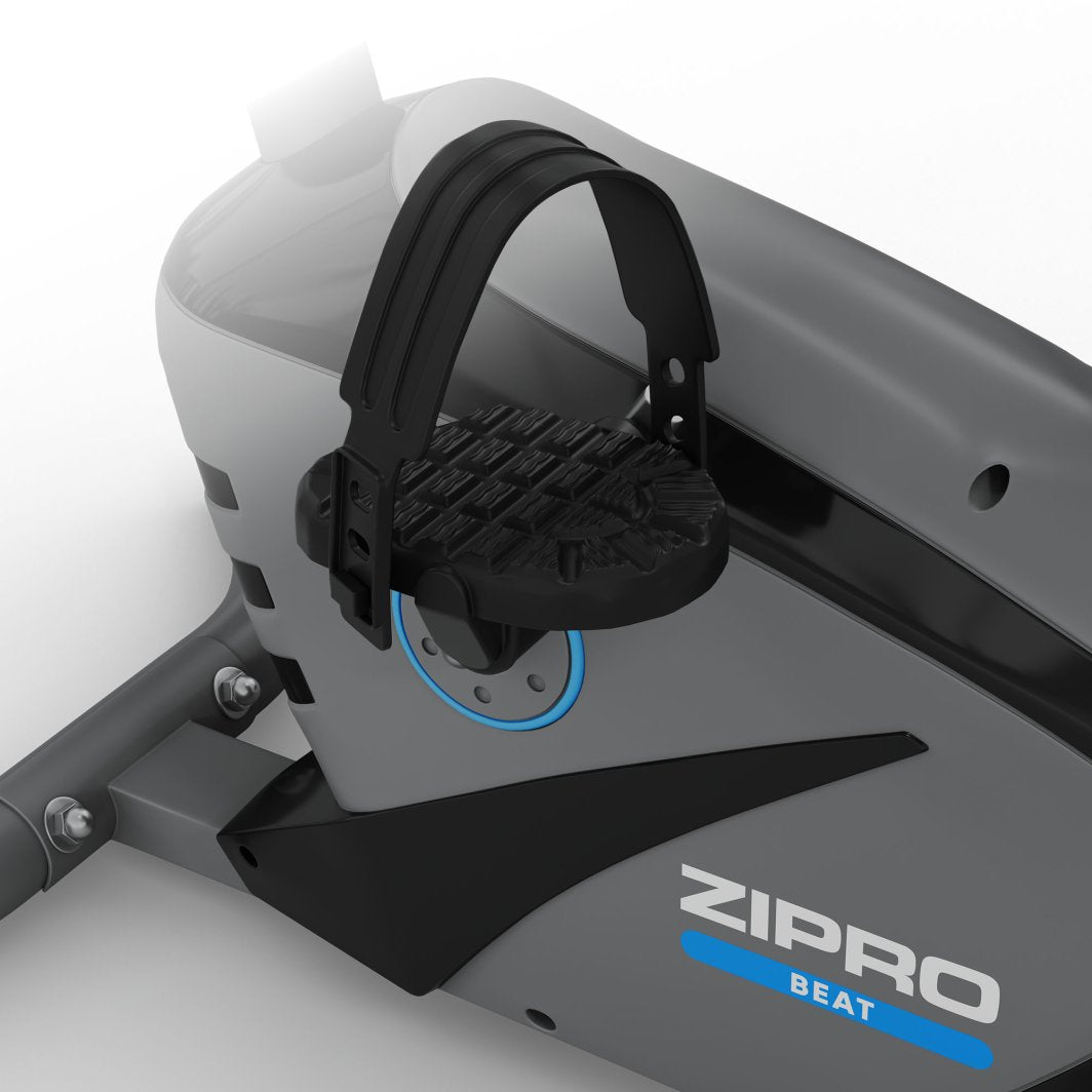 Treningssykkel med svart pedal og justerbar fotstropp, riflet overflate og delvis synlig logo på siden.