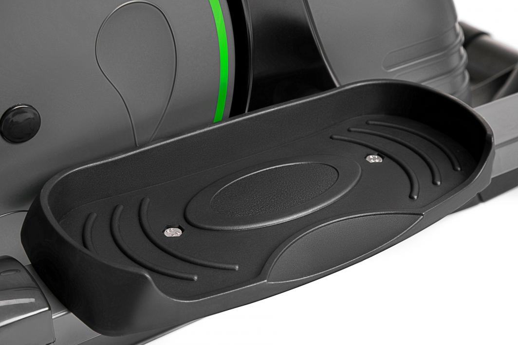 Crosstrainer sort plastfotplate med riflet, sklisikkert mønster, to skruer og grå maskindel i bakgrunnen.