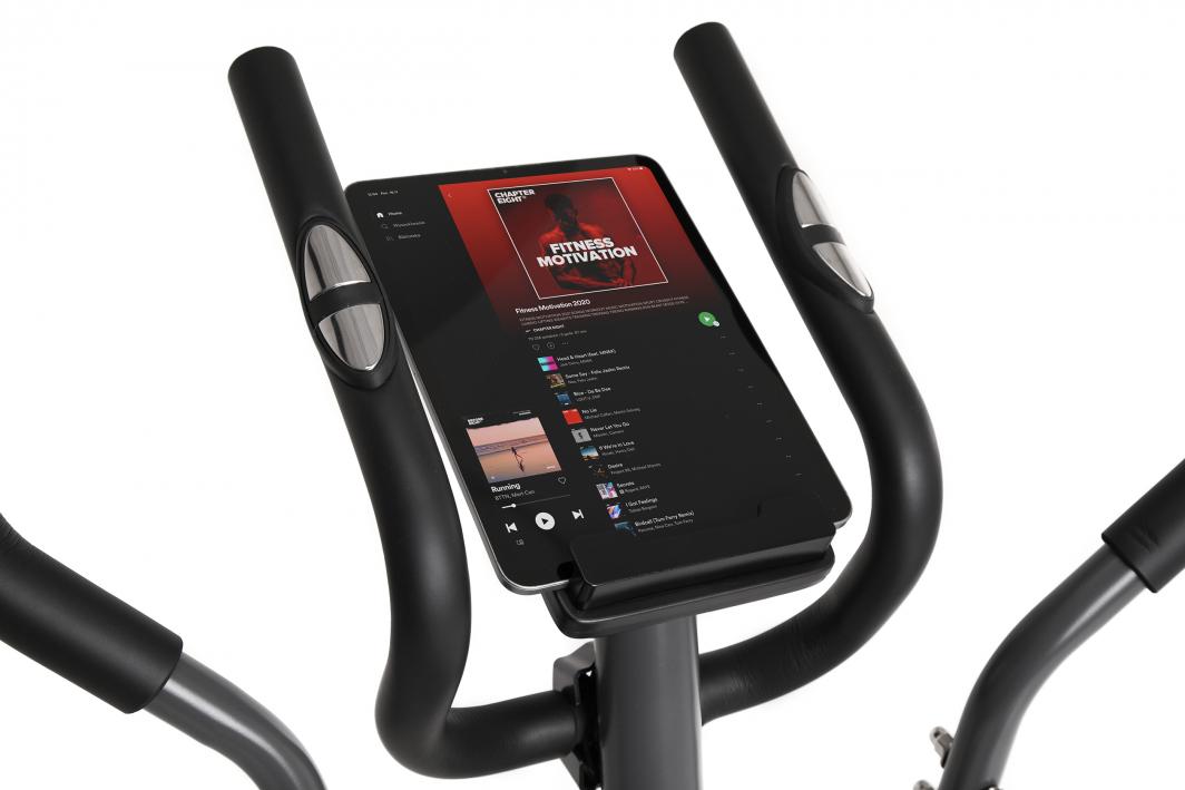 Crosstrainer med sorte håndtak, pulssensorer og nettbrett-holder med musikkspilleliste, sett ovenfra.