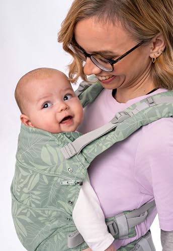 Bæresele Baby i grønn med bladmotiv bæres av voksen med barn, tydelig sele og barnets ansikt fra siden.