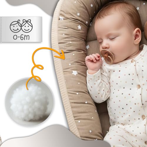 Babynest i beige med stjernemønster, småbarn sover inni, nærbilde viser mykt fyll og etikett med tegning.