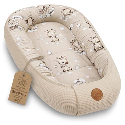 Babynest i beige vaffelmønstret bomull med sjiraffmotiv, rektangulær form, brun etikett og skinnmerke.