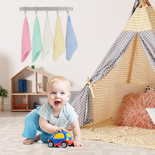 Baby Kluter henger fargerikt på veggen bak en baby som leker med lekebil i lyst barnerom med lekethus og tipi-telt.