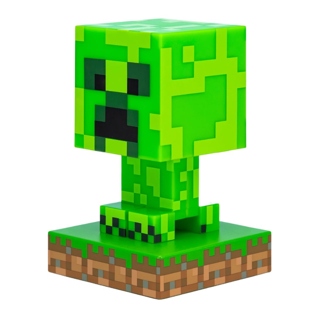 Bordlampe formet som grønn, pikselert Minecraft Creeper-figur på jord- og gressmønstret sokkel, sett skrått forfra.
