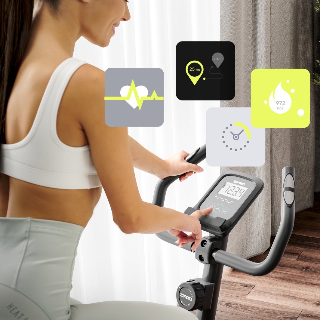 Treningssykkel brukt av kvinne i treningstøy, nærbilde av skjerm og håndtak med ikoner for puls og distanse.