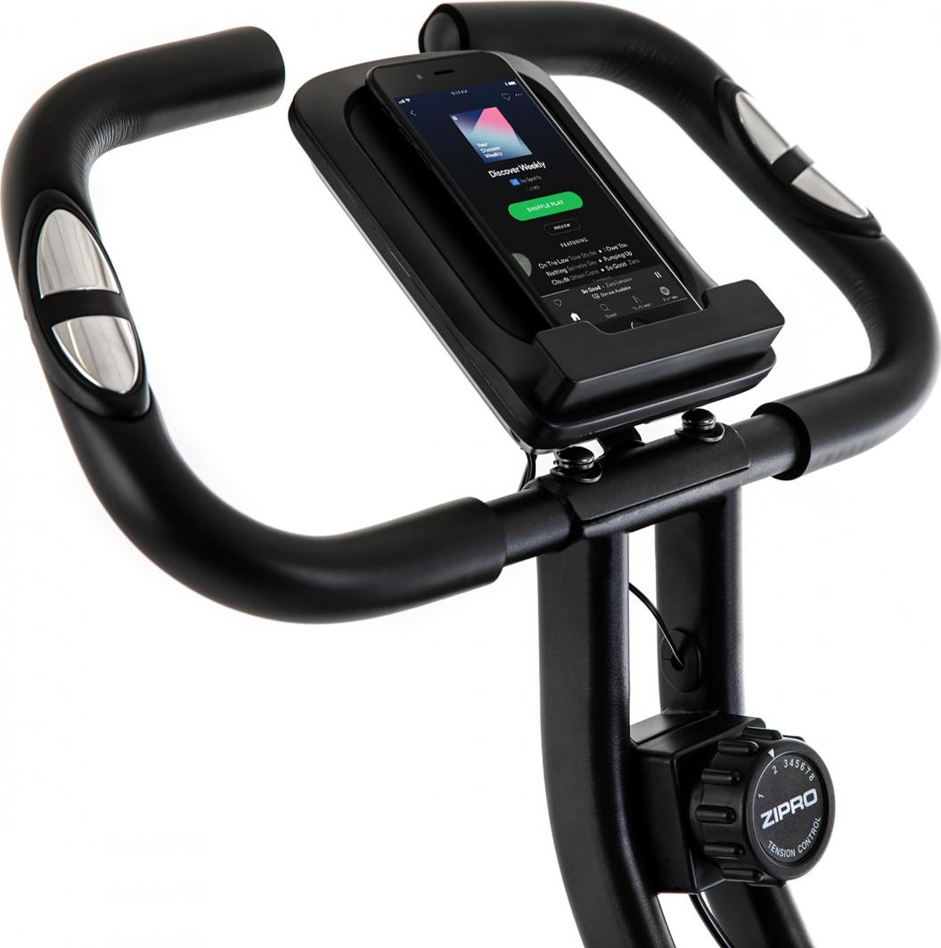 Treningssykkel med svart styre, integrert pulssensor, motstandsbryter og mobilholder med mobil, sett skrått ovenfra.