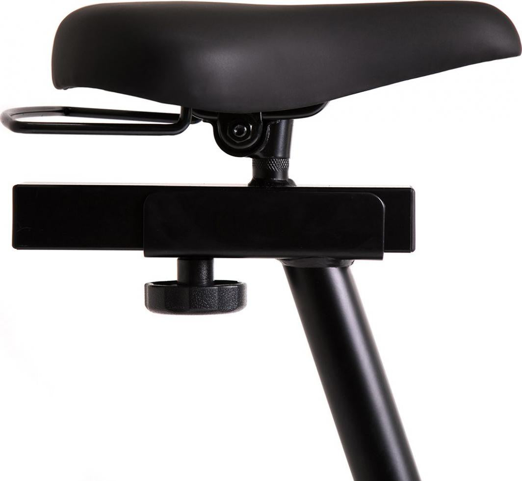Ergometersykkel sort sete med justeringsmekanisme, myk polstring og metallstøtte, sett fra siden.