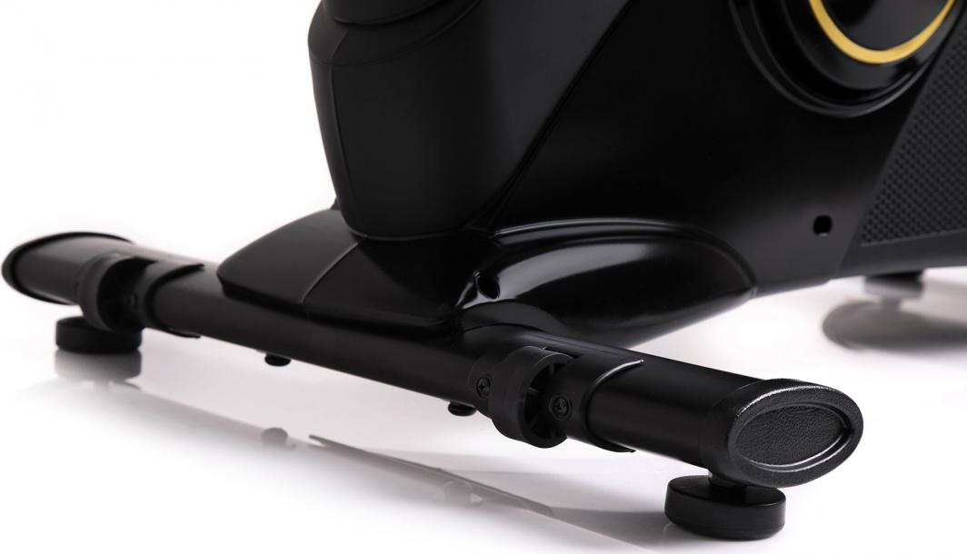 Ergometersykkel med sort, metallisk fotstøtte og justerbare føtter, sett fra siden med glinsende overflate.