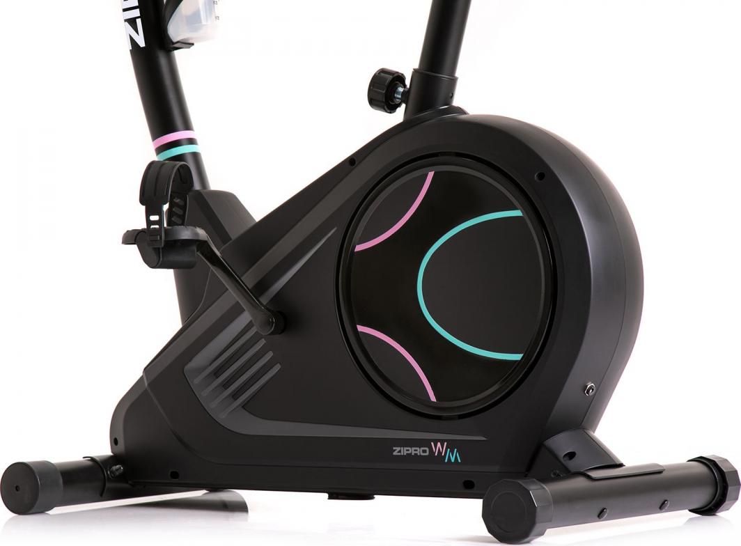 Spinningsykkel med detaljbilde av pedal og drivverk i sort plast, dekorert med blå og rosa linjer, sett fra siden.