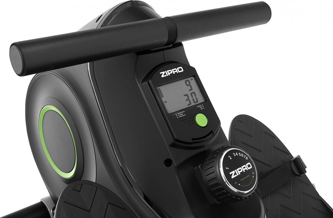 Romaskin Trening sort modell med grønne detaljer, digital skjerm og justerbare pedaler, sett skrått forfra.