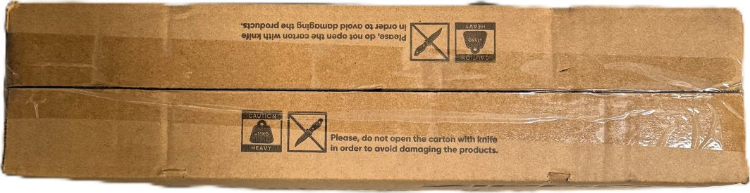 Manualsett i brun pappeske sett ovenfra, forseglet med klar tape og varsling om tung vekt og knivforbud.