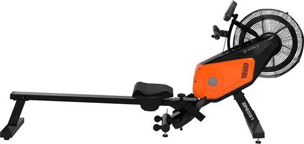 Romaskin med oransje og svart ramme, sete på skinne, stort viftemotstandshjul, synlige pedaler og håndtak.