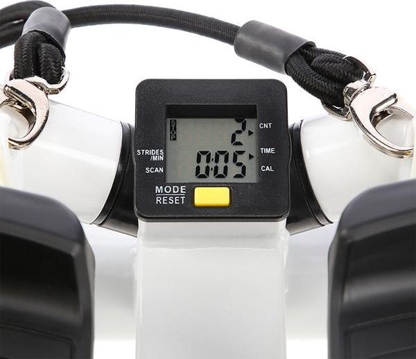 Mini Stepper med digitalt display sett forfra, viser tid og steg, hvit og svart med gule knapper og treningsstrikker.