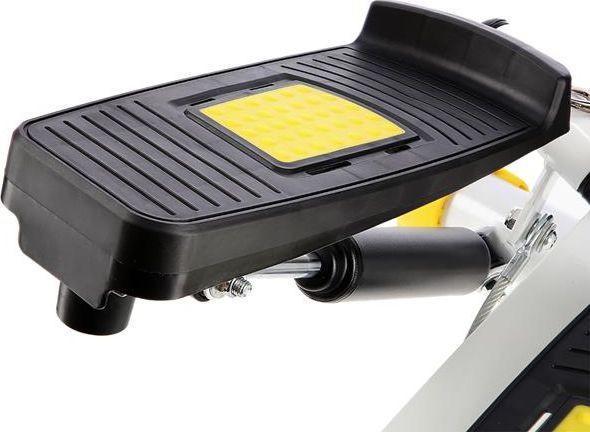 Stepper Trening sort fotplate med gult mønster, sett fra siden med synlige metallkomponenter under platen.