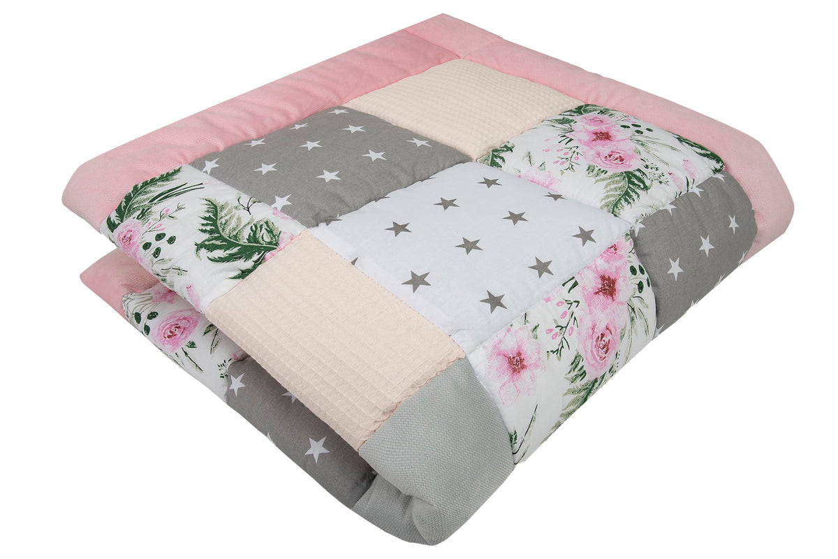 Lekematte i lyse farger med rosa, grått og hvitt, stjernemønster og blomster, vist sammenbrettet fra skrå vinkel.